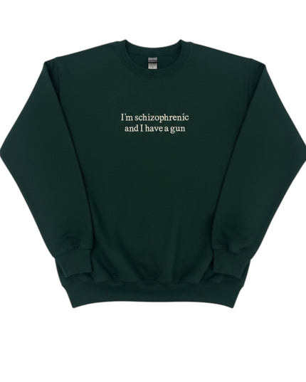 A dark green sweatshirt with the text "I'm schizophrenic and I have a gun" printed on it.