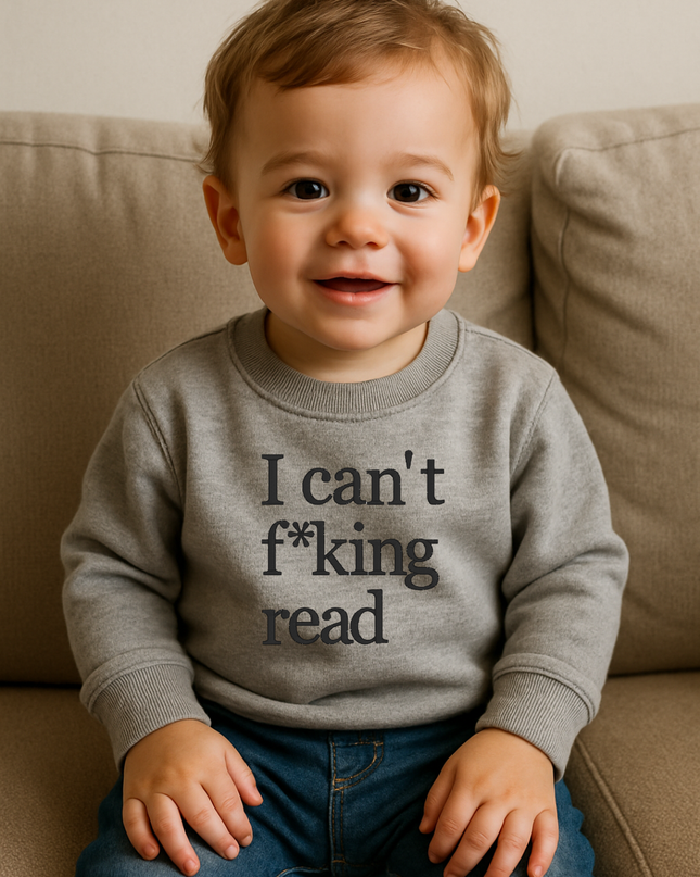 A smiling baby boy wearing a gray sweatshirt with the text "I can't f*king read" printed on it.