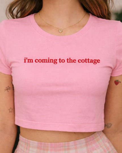 A woman wearing a pink crop top with the text "I'm coming to the cottage" printed on it.