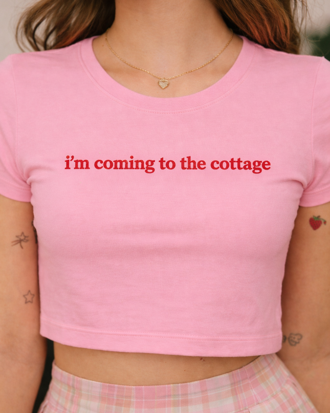 A woman wearing a pink crop top with the text "I'm coming to the cottage" printed on it.