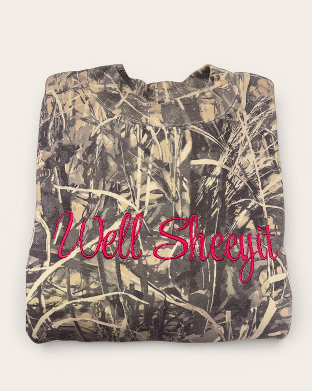 A camouflage-patterned t-shirt with the text "Well Sheeytit" embroidered on it.