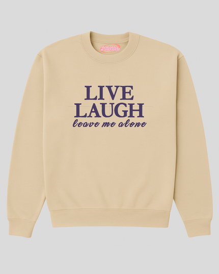A beige sweatshirt with the text "LIVE LAUGH leave me alone" printed on it in purple.