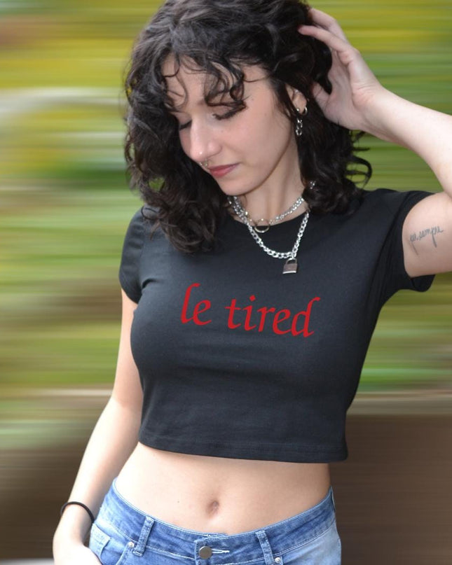 a woman wearing a black crop top with the word le tried on it