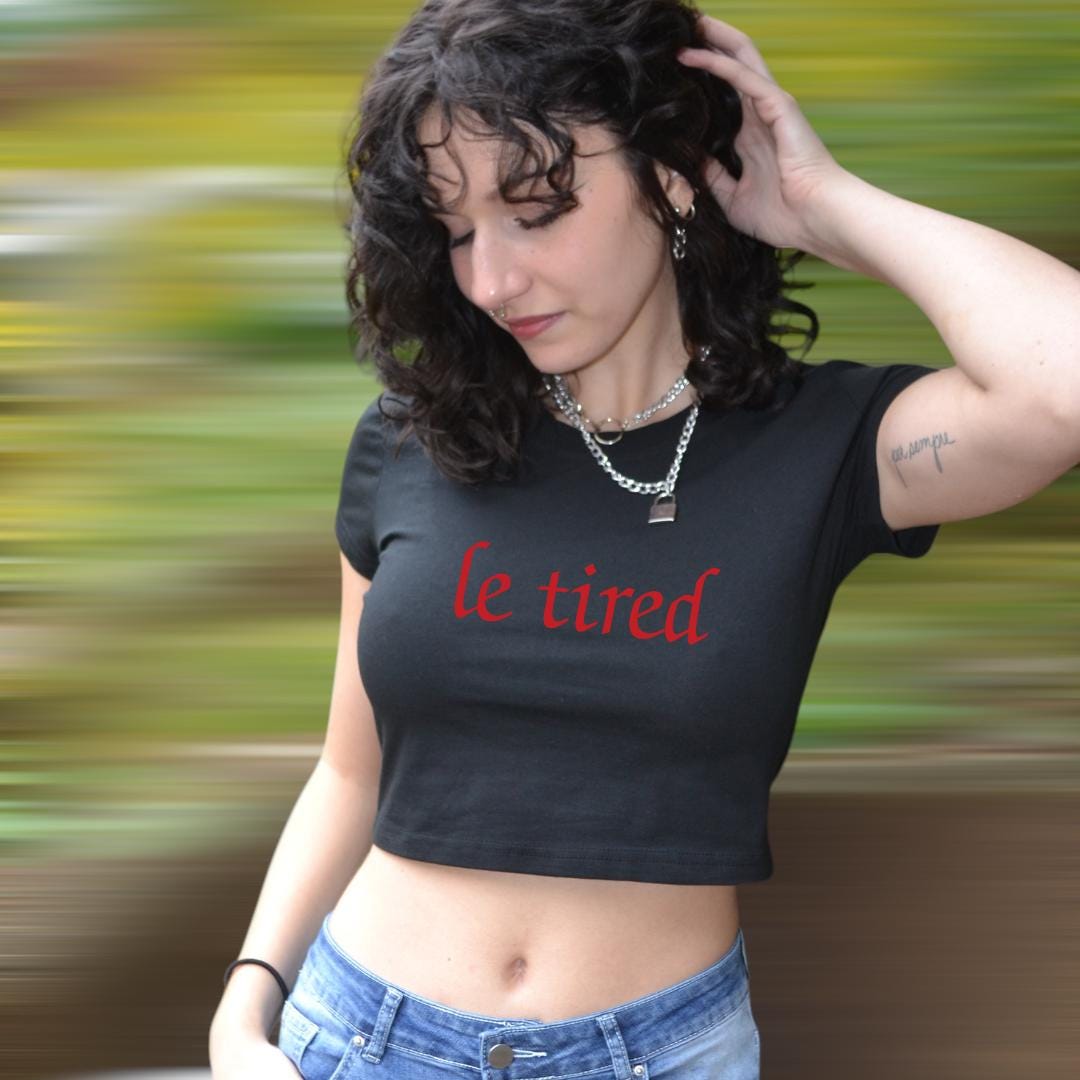 a woman wearing a black crop top with the word le tried on it