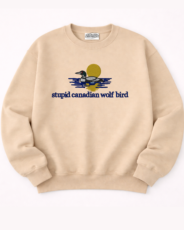 A beige sweatshirt with a graphic design depicting a duck swimming on a body of water, accompanied by the text "stupid canadian wolf bird".