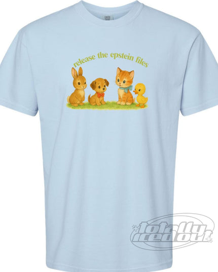 A light blue t-shirt with a graphic design featuring a rabbit, a dog, a cat, and a bird on a grassy field. The text above the image says "release the Epstein files".