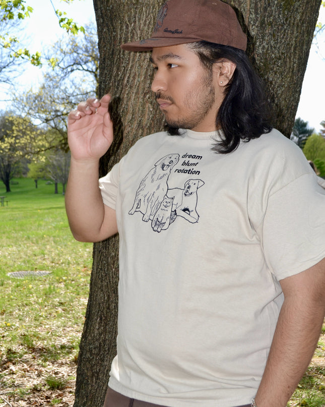 a man standing next to a tree wearing a hat