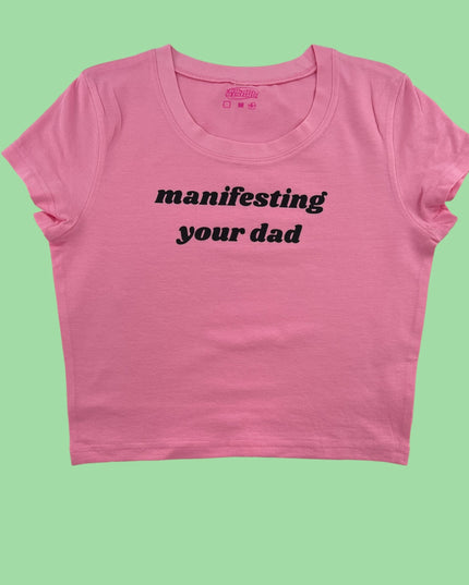 a pink crop top with the words manifisting your dad printed on it