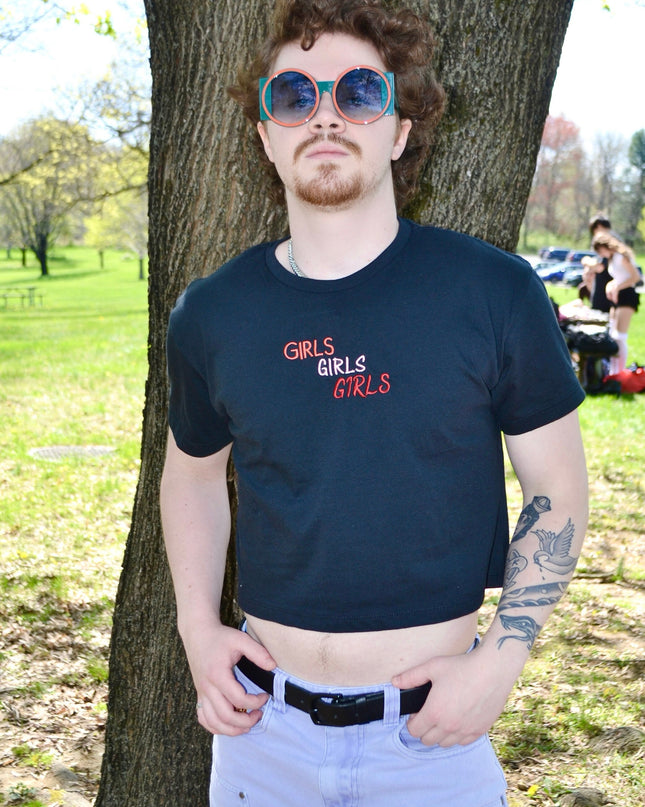 a man wearing sunglasses standing next to a tree