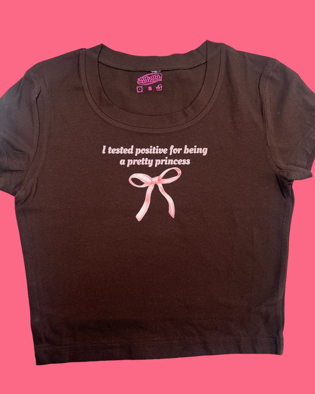 a brown shirt with a pink ribbon on it