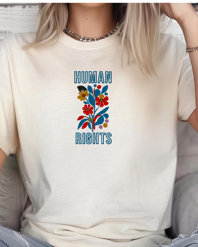A person wearing a white t-shirt with a graphic design that says "HUMAN RIGHTS" and features a colorful flower-like design.