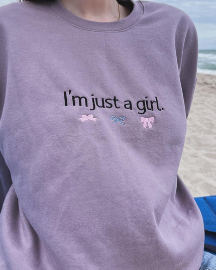 a woman sitting on the beach wearing a sweatshirt that says i'm just a
