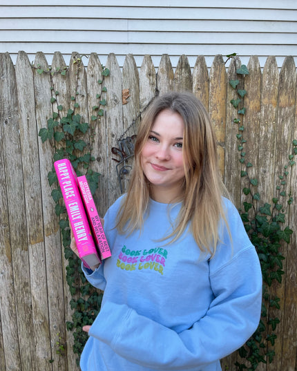a girl in a blue sweatshirt holding a pink tube