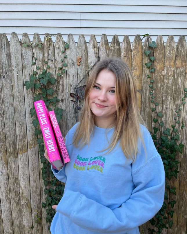 a girl in a blue sweatshirt holding a pink tube