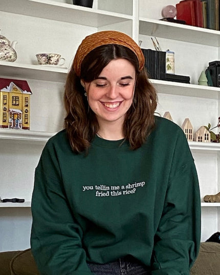 a woman sitting on a couch wearing a green sweatshirt