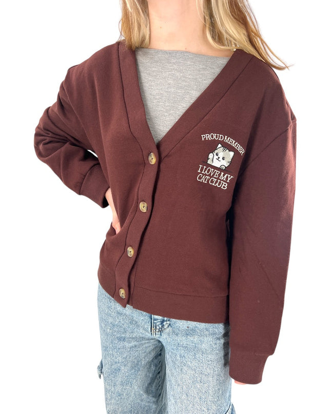 a woman wearing a brown cardigan with a white dog on it