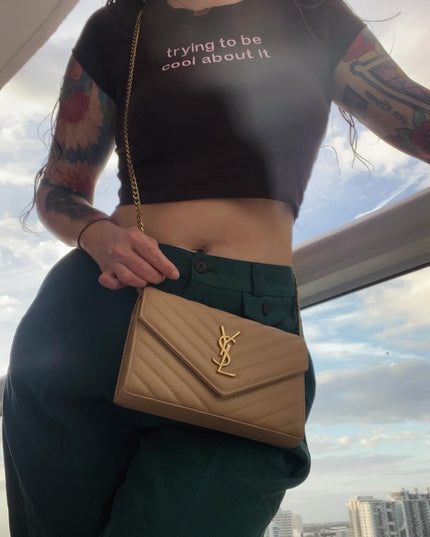 a woman with tattoos holding a tan purse