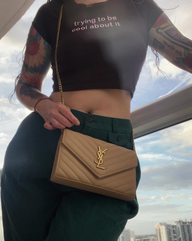 a woman with tattoos holding a tan purse
