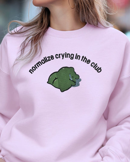 a woman wearing a pink sweatshirt with a green bear on it