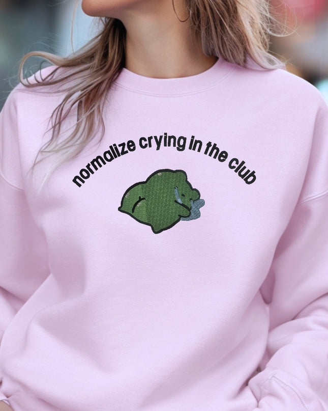 a woman wearing a pink sweatshirt with a green bear on it