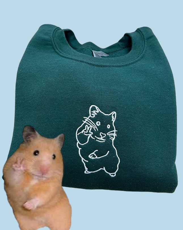 a hamster sitting next to a green bag
